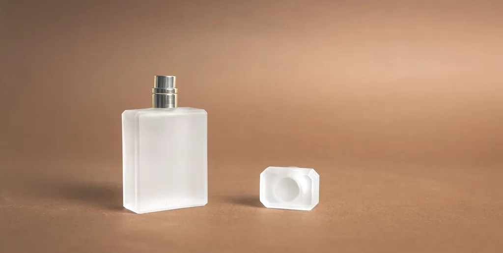 شیشه‌ی عطر روی زمینه‌ی گرم